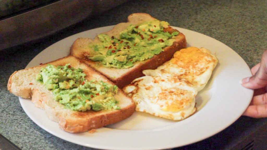 avocado toast with eggs over medium on a white plate