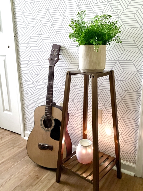 guitar next to a beautiful fern on a plant stand