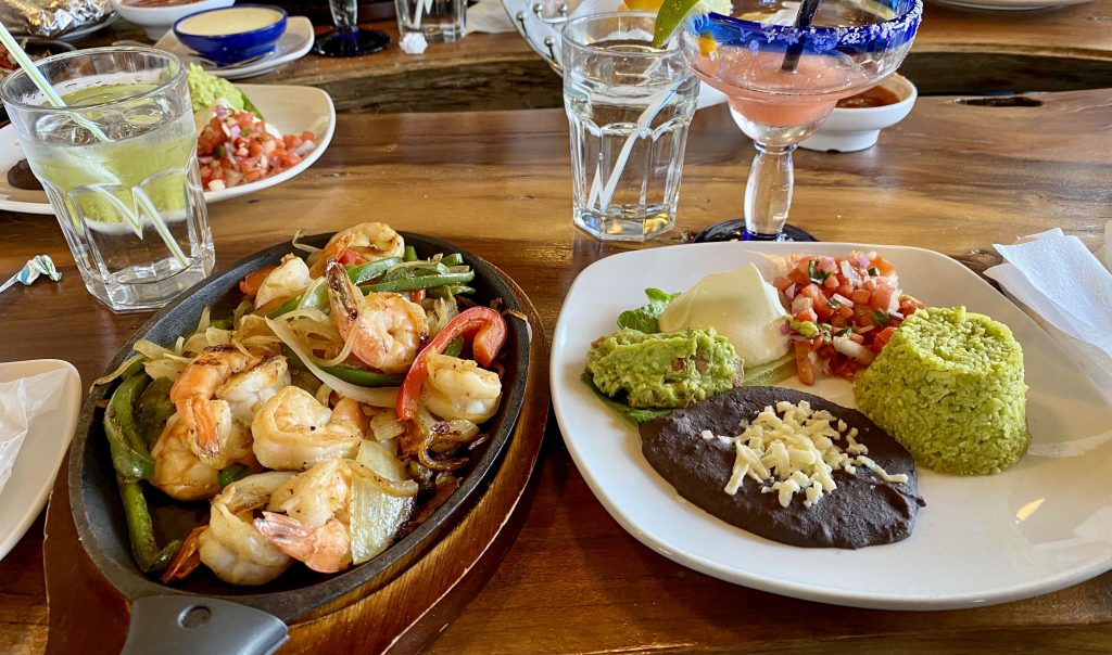 photo of shrimp, guacamole, salsa, rice, and beans on a table at a Mexican restaurant