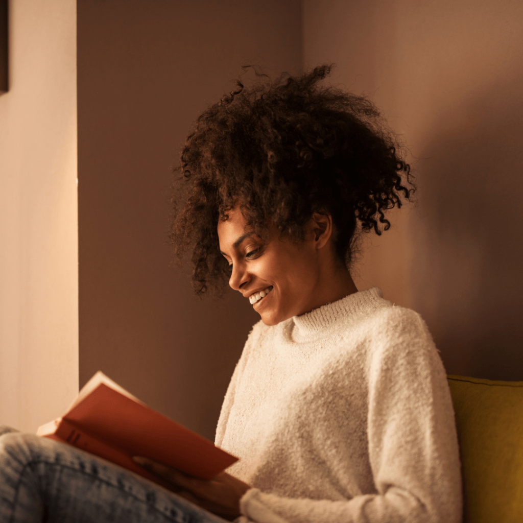 girl sitting on couch and smiling while reading a book