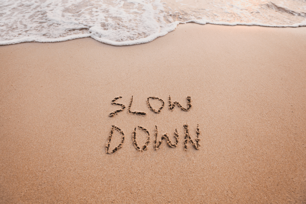 slow down written on the sand at a beach