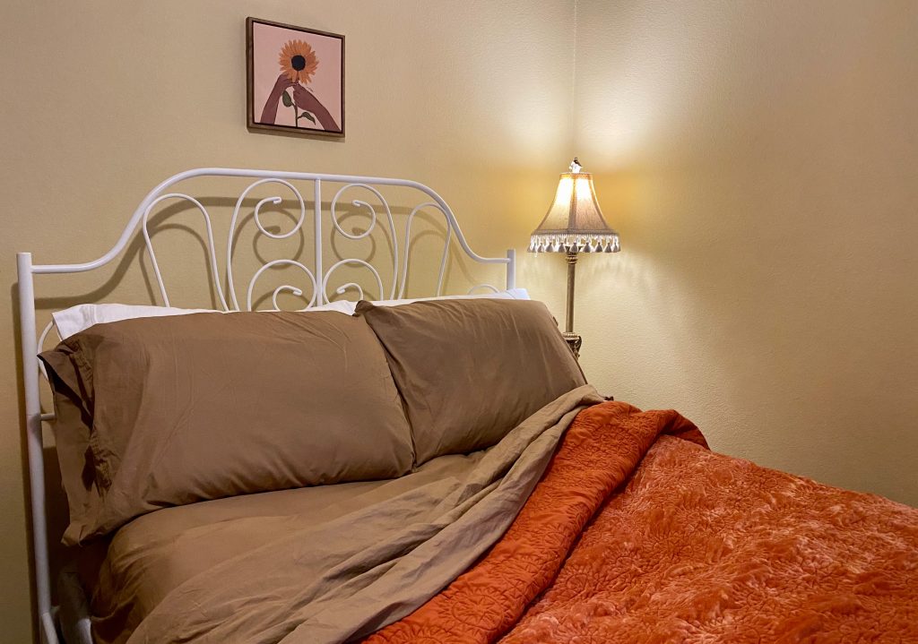 cozy bed with brown sheets and an orange comforter