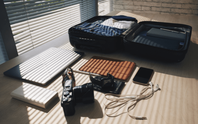 mobile phone and camera supplies next to an open carry-on suitcase