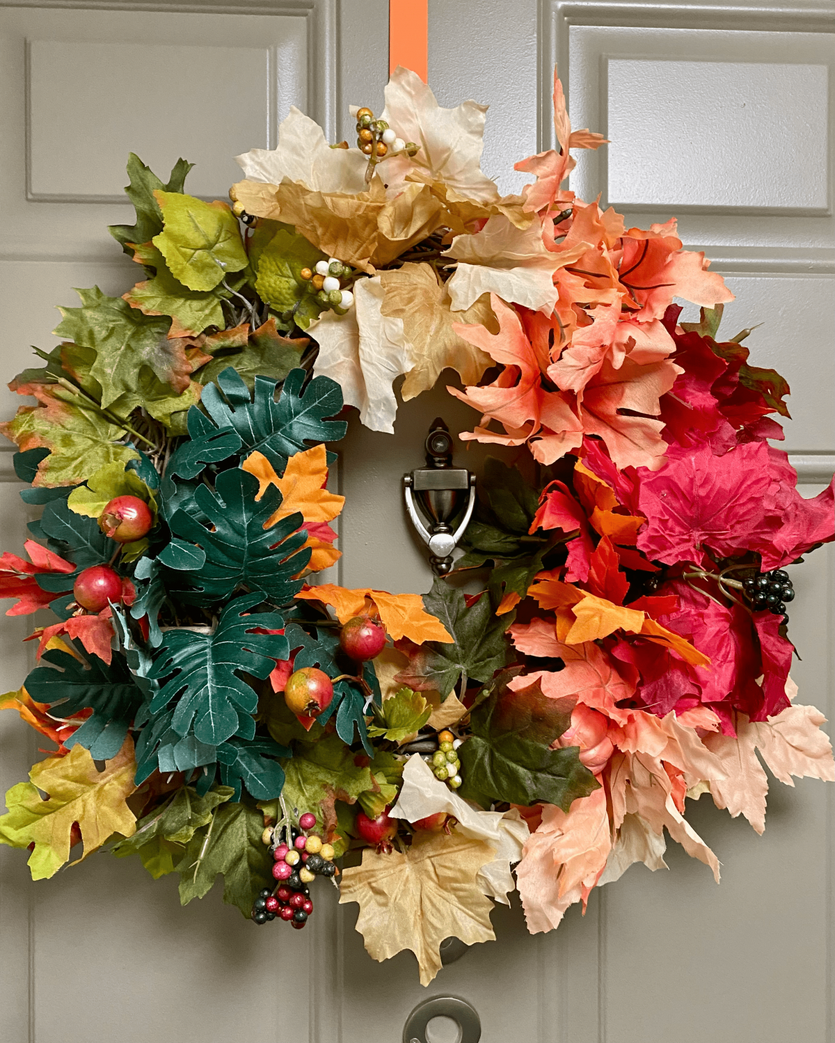 fall wreath with colorful leaves hanging on door