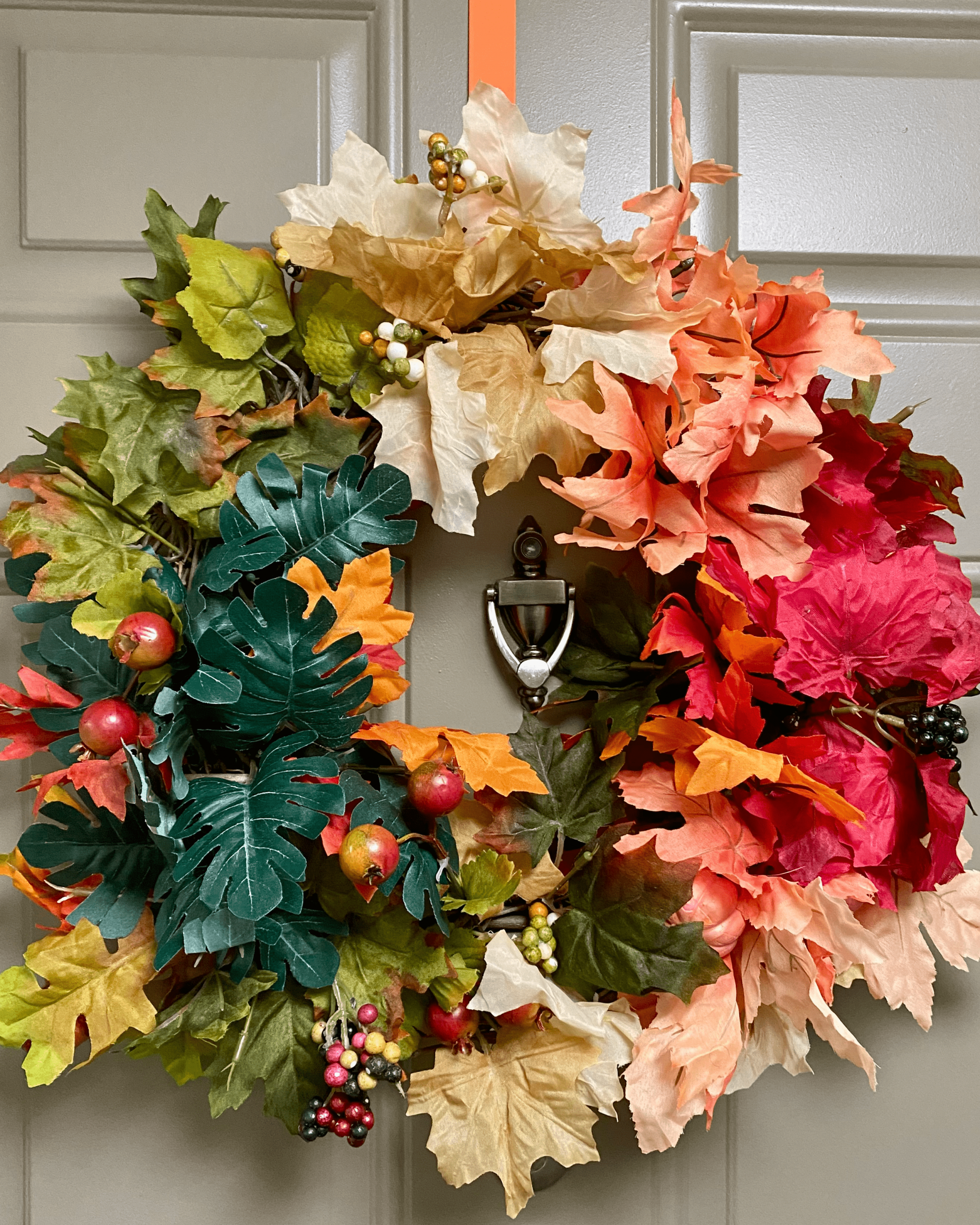 fall wreath with colorful leaves hanging on door