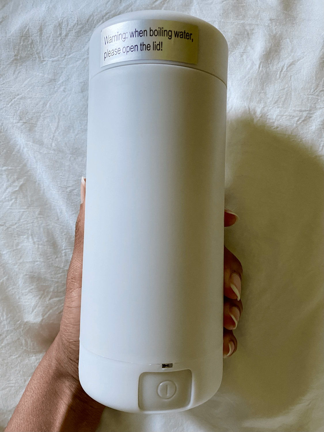 hand holding a white travel electric water kettle