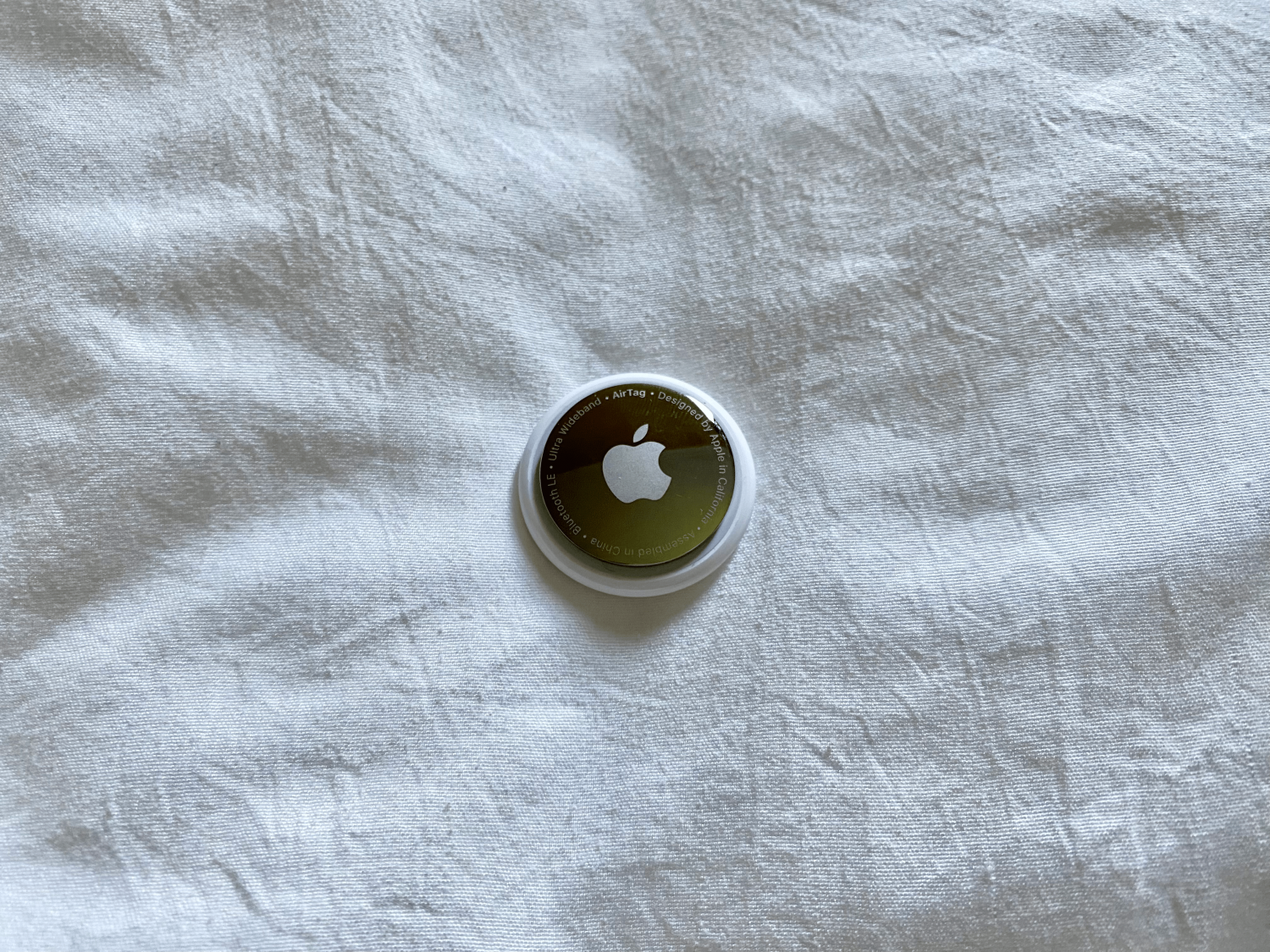 Apple AirTag on a white linen sheet